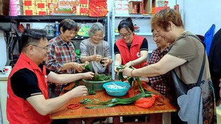 志愿者与老人们一起包粽子。缪莉莉摄