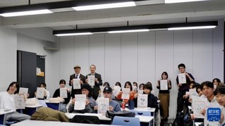 12月19日，在日本东京都的中央大学，学生们举着自己制作的木版水印画合影。新华社发