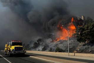 12月5日，在美国加利福尼亚州南部文图拉县，消防车经过一处着火建筑。新华社/路透