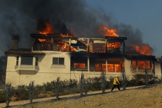 12月5日，在美国加利福尼亚州南部文图拉县，消防员经过一处着火房屋。新华社/路透