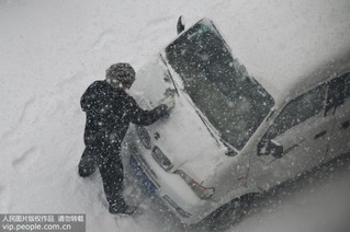 12月11日，山东省烟台市市民在清理车上积雪。