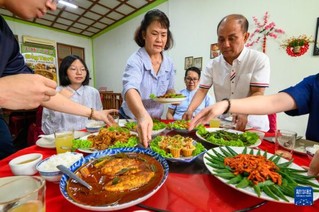 12月4日，在马来西亚马六甲，小娘惹餐馆老板娘黄露丝（中）上菜。新华社发（张纹综摄）