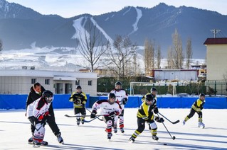 新疆乌鲁木齐市乌鲁木齐县第一中学小学部冰球队的学生在进行冰球比赛（2022年1月12日摄）。