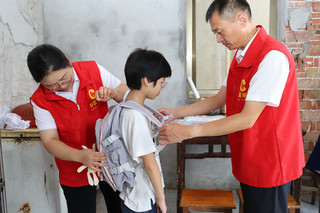 如东“金叶”志愿者为儿童送上新书包。如东烟草供图