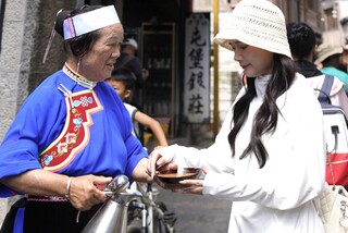 1 图为7月23日，安顺天龙屯堡内，一位穿着传统服装的居民为游客倒茶。  王珏玮 摄