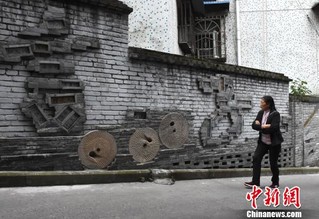 图话中国   一摩托车驶过老街道"重庆言子"墙.