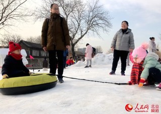 看冰雕、滑雪车，前门三里河附近的小朋友有了玩雪的好去处。人民网 董兆瑞摄