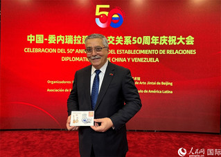 中国—委内瑞拉建立外交关系50周年庆祝大会上，委内瑞拉驻华大使朱塞佩•约夫雷达展示《中委建交五十周年》纪念明信片。人民网记者 吴思萱摄