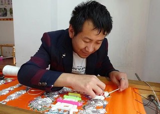 彭宗旺正在认真刺绣。南华县融媒体中心供图