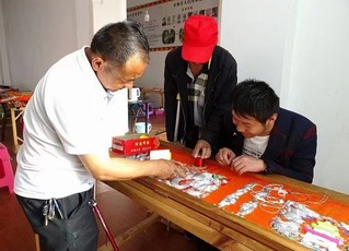 彭宗旺正在和工友讨论刺绣。南华县融媒体中心供图