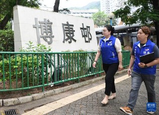   4月18日，博康关爱队队长、沙田区区议员郭宣彤（左）与队员从博康邨内走过。新华社记者 陈铎 摄