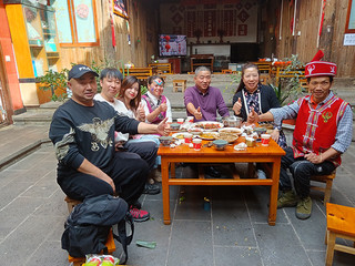 李发顺（右一）和妻子（左四）与游客围桌而坐，幸福的笑容在他们的脸上绽放。受访者供图