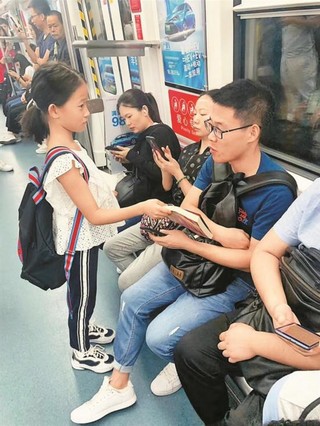 深圳小学生给地铁"低头族"送书