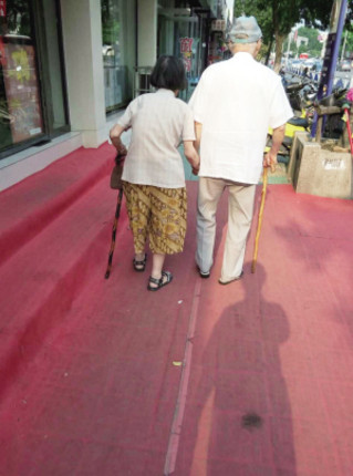 在正东路上,一对拄着拐杖牵手的老夫妻,慢慢走在红毯上.