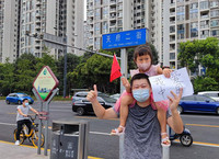 2021年8月11日，成都一小区解除疫情管控后，居民走上街头。一对父女写下“我爱中国”，表达了对抗疫人员的感恩之情。罗毅然供图
