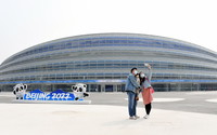 建設者張博偉（左）與家屬在國家速滑館“冰絲帶”外合影留念（4月10日攝）。