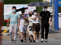 7月10日，在上海市闵行区，行人在烈日下行走。